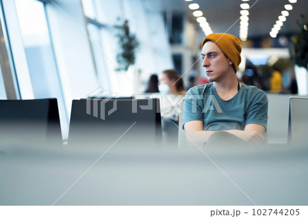 Man is sitting at the airport, waiting for flight. Man is sitting at the airport, waiting for flight. 102744205
