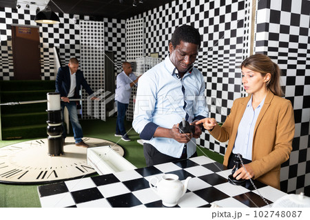Colleagues playing in chess quest room during team building 102748087
