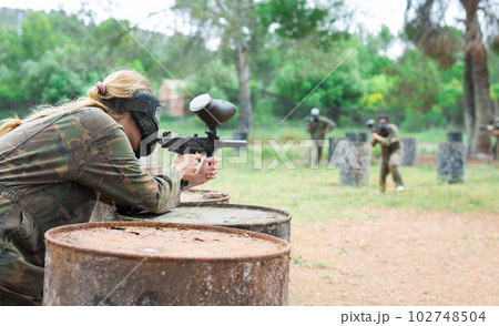 Woman paintball player in mask aiming with gun 102748504