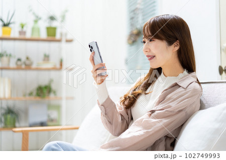 ソファーに座ってスマホを見る女性 ソファーに座ってスマホを見る女性 102749993