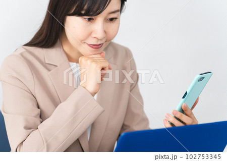 ノートパソコンとスマートフォンを使う若い女性 ビジネスイメージ ノートパソコンとスマートフォンを使う若い女性 ビジネスイメージ 102753345