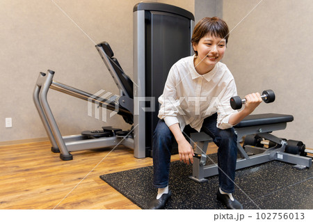 フィットネスジムで普段着でパーソナルトレーニングをする若い女性　コンビニジムイメージ 102756013