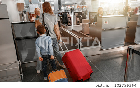 Mom and son holding suitcases and going through passport control 102759364