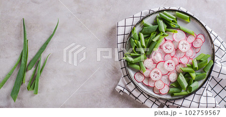 Spring homemade radish and chives salad on a plate on the table top view web banner 102759567