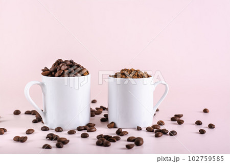 Roasted coffee beans and instant coffee in cups on pink background 102759585