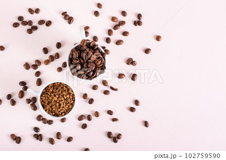 Roasted coffee beans and instant coffee in cups on pink background top view Roasted coffee beans and instant coffee in cups on pink background top view 102759590