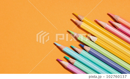 Colored pastel pencils corner border on orange. Back to School or drawing and creativity concept. Copy space. Top view Colored pastel pencils corner border on orange. Back to School or drawing and creativity concept. Copy space. Top view 102760137