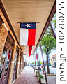 A bustling street in Abilene, Texas with the exterior of a Texas Star Trading building displaying a hanging Texas flag. 102760255