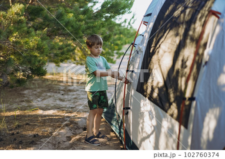 cute little caucasian boy helping to put up a tent. Family camping concept cute little caucasian boy helping to put up a tent. Family camping concept 102760374