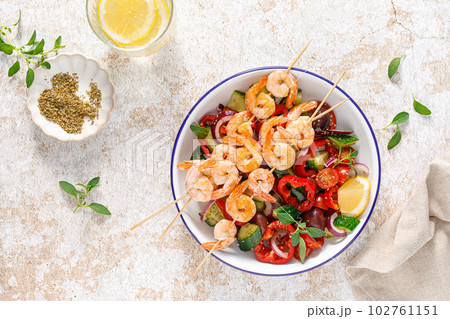 Shrimp kebab roasted on skewers and fresh vegetable salad, top view Shrimp kebab roasted on skewers and fresh vegetable salad, top view 102761151
