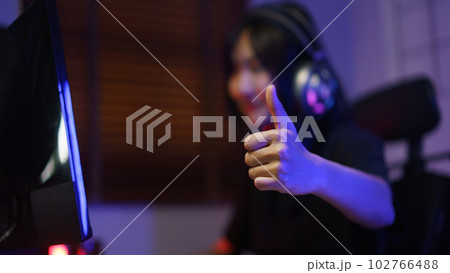 Female cyber hacker gamer in headphone showing thumb up after hacking programming system success Female cyber hacker gamer in headphone showing thumb up after hacking programming system success 102766488