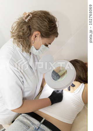 Dermatologist Removes Hair With Electrolysis Procedure On Woman's Back, Electric Epilation In Beauty Salon. Vertical Plane. Authentic Photo Dermatologist Removes Hair With Electrolysis Procedure On Woman's Back, Electric Epilation In Beauty Salon. Vertical Plane. Authentic Photo 102768069