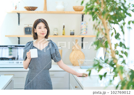 キッチンでコーヒーを飲む若い女性 102769012