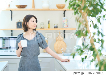 キッチンでコーヒーを飲む若い女性 キッチンでコーヒーを飲む若い女性 102769013