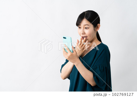 スマートフォンを持ちながらビックリをする若い女性 スマートフォンを持ちながらビックリをする若い女性 102769127