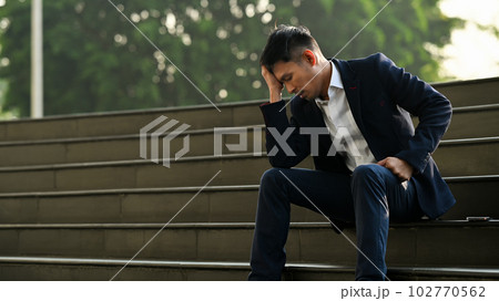 Image of upset man employee sitting on stairs outside office building, financial crisis, unemployed concept 102770562
