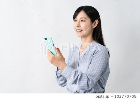 笑顔でスマートフォンを持ちながらスワイプをする若い女性 笑顔でスマートフォンを持ちながらスワイプをする若い女性 102770709