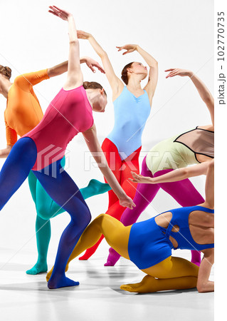 Modern choreography. Group of young girls, ballet dancers in colorful clothes dancing against grey background. Cropped. 102770735