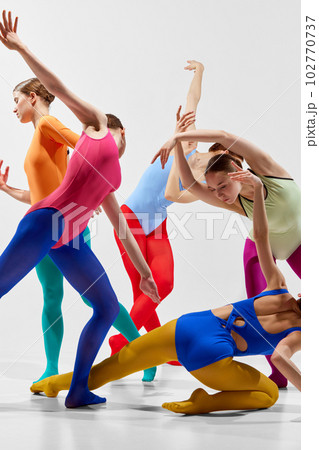 Cropped, close-up image of young girl. ballerinas in bright, multicolored tights and bodysuits dancing over grey background 102770737