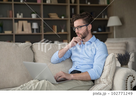 Serious pensive freelancer man in glasses relaxing on sofa Serious pensive freelancer man in glasses relaxing on sofa 102771249