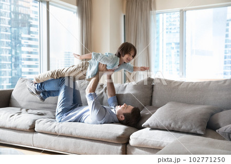 Strong dad lying on back, lifting happy little son up Strong dad lying on back, lifting happy little son up 102771250