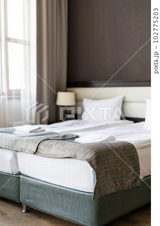 double bed with white bedclothing and towels in room in gray brown interior by the window hotel apartments modern design 102775203
