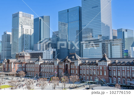 東京都千代田区丸の内　快晴のJR東京駅（重要文化財の丸の内駅舎）と周辺の高層ビル群 102776150
