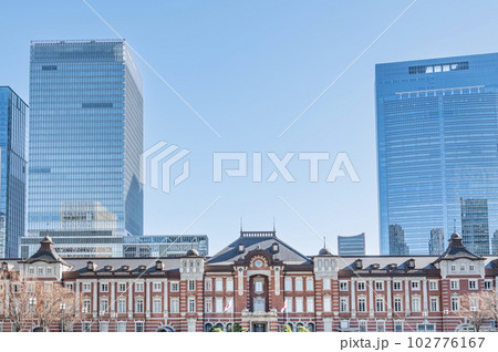 東京都千代田区丸の内　快晴のJR東京駅（重要文化財の丸の内駅舎）と周辺の高層ビル群 102776167