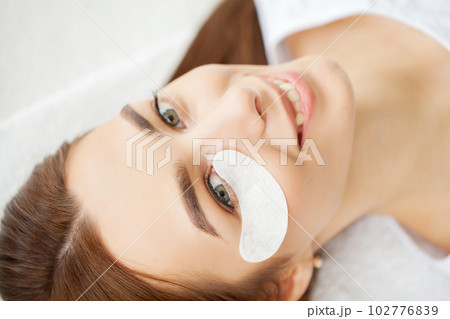 Eyelash extension procedure, master fake long lashes beautiful female eyes. 102776839