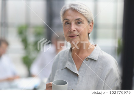 close-up mature woman holding a cup in the office close-up mature woman holding a cup in the office 102776979