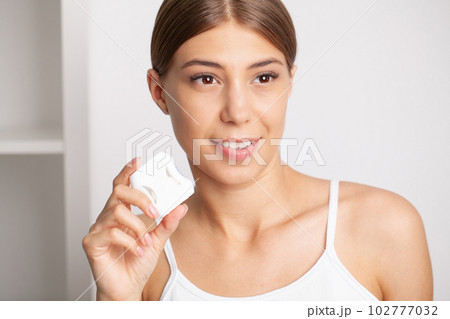 Woman using dental floss for cleaning her teeth 102777032