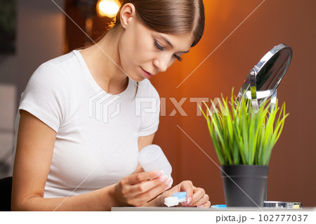 Woman holds contact lens on her finger, eye care and the choice between the means to improve vision. Woman holds contact lens on her finger, eye care and the choice between the means to improve vision. 102777037