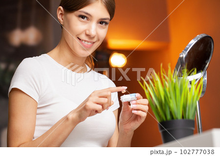 Young woman putting contact lens in her eye, close up 102777038