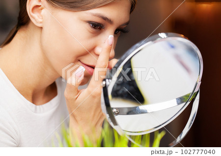 Young woman putting contact lens in her eye, close up Young woman putting contact lens in her eye, close up 102777040