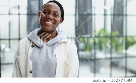 Smiling young woman standing and looking at the camera. 102777094