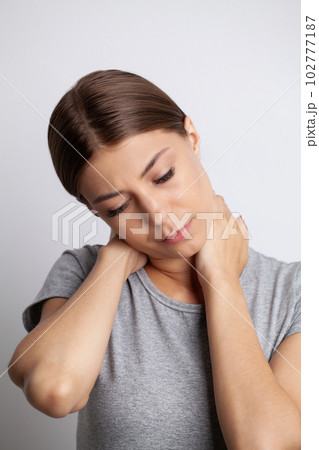 Young woman feeling exhausted and suffering from neck pain, health concept. 102777187