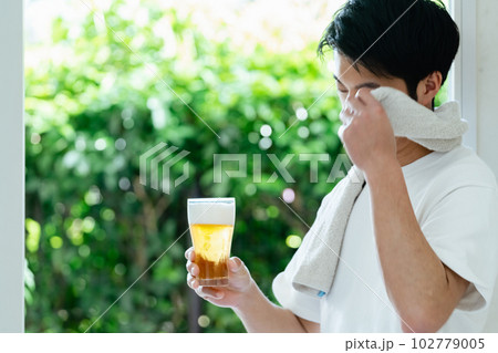 休日にビールを飲む男性 102779005