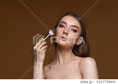 woman applying blush on cheeks with make-up brush woman applying blush on cheeks with make-up brush 102779664