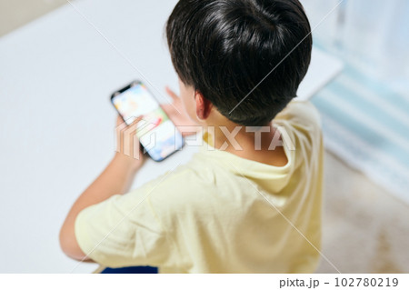 スマホで動画を視聴する小学生の男の子 スマホで動画を視聴する小学生の男の子 102780219