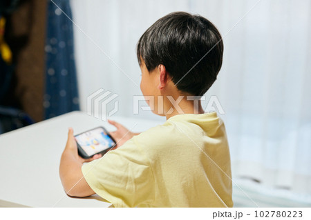 スマホでゲームをする小学生の男の子 スマホでゲームをする小学生の男の子 102780223