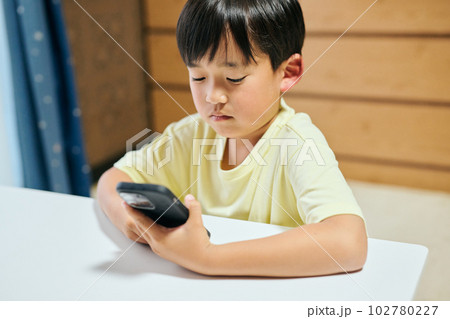 スマホで動画を視聴する小学生の男の子 スマホで動画を視聴する小学生の男の子 102780227