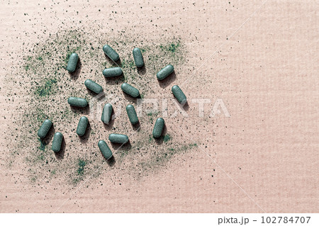 Organic chlorella, spirulina or barley grass powder pills on beige paper background in eco style copy space 102784707