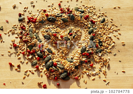 Food background of mix of spices, condiments and seeds close up with selective focus in the shape of a heart on a wooden board Food background of mix of spices, condiments and seeds close up with selective focus in the shape of a heart on a wooden board 102784778