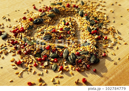 Food background of mix of spices, condiments and seeds close up with selective focus in the shape of a heart on a wooden board 102784779