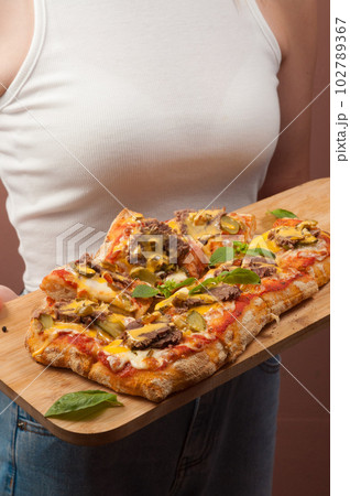 a girl in a white tank top holds an Italian pizza 102789367