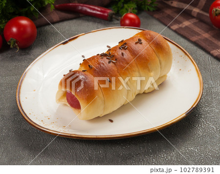 sausage in dough with sesame seeds on a light plate sausage in dough with sesame seeds on a light plate 102789391