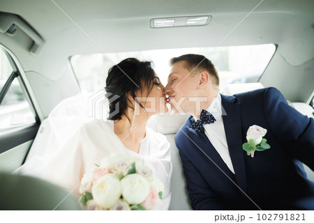 Beautiful bride and groom embracing and kissing on their wedding day in a car 102791821