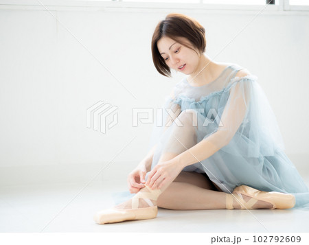 明るい室内でトゥシューズを履く女性 102792609
