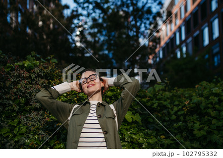 Portrait of young woman enjoying nature in city park. 102795332