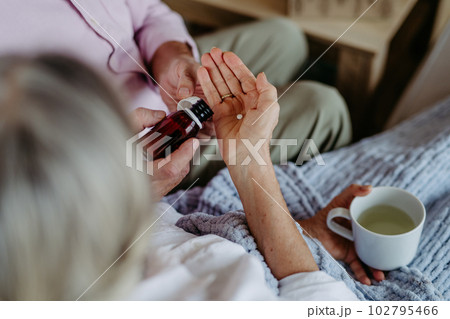 Close up of senior man giving medicines to his ill wife. 102795466